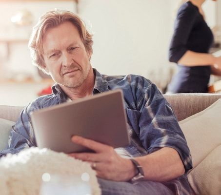 A man sits and reads about buy to let mortgages on his tablet